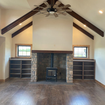 Vaulted living room ceiling with exposed beams, custom built-ins, and pellet fir