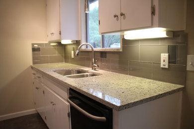 Small transitional u-shaped slate floor enclosed kitchen photo in Austin with an undermount sink, white cabinets, granite countertops, glass tile backsplash, stainless steel appliances, flat-panel cabinets, gray backsplash and no island