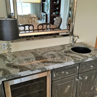 他の地域の小さいトランジショナルスタイルのおしゃれなウェットバー (アンダーカウンターシンク、レイズドパネル扉のキャビネット、グレーのキャビネット、クオーツストーンカウンター、トラバーチンの床、ベージュの床) の写真