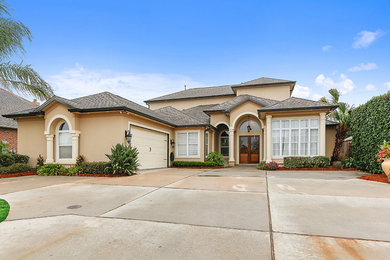 Large tuscan beige two-story stucco exterior home photo in New Orleans