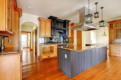 Large elegant u-shaped dark wood floor enclosed kitchen photo in Tampa with an undermount sink, raised-panel cabinets, medium tone wood cabinets, granite countertops, black backsplash, ceramic backsplash, stainless steel appliances and an island