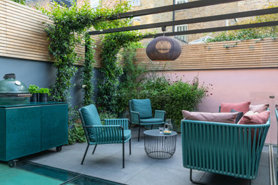 Small contemporary back patio in London with a bbq area, tiled flooring and a pergola.
