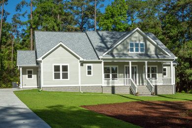 Photo of a mid-sized traditional one-storey grey house exterior with vinyl siding, a gable roof, a shingle roof, a grey roof and clapboard siding.