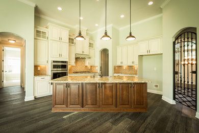 Inspiration for a mid-sized transitional l-shaped dark wood floor and gray floor open concept kitchen remodel in Jacksonville with an undermount sink, recessed-panel cabinets, white cabinets, granite countertops, beige backsplash, stone tile backsplash, stainless steel appliances and an island