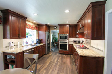 Example of a mid-sized transitional l-shaped porcelain tile and brown floor enclosed kitchen design in San Francisco with an undermount sink, raised-panel cabinets, dark wood cabinets, granite countertops, white backsplash, subway tile backsplash, stainless steel appliances, no island and beige countertops