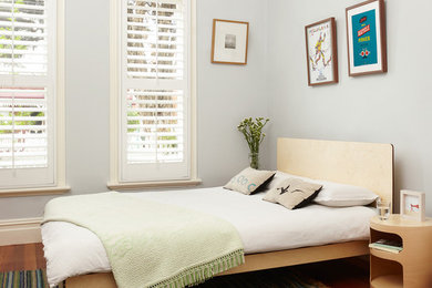 Photo of a contemporary bedroom in Melbourne with grey walls and medium hardwood floors.