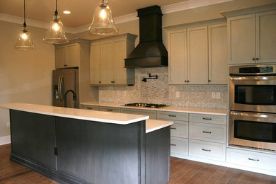 Kitchen - craftsman medium tone wood floor kitchen idea in Miami with a farmhouse sink, recessed-panel cabinets, green cabinets, quartzite countertops, multicolored backsplash, mosaic tile backsplash, stainless steel appliances and an island
