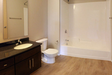 Example of a mid-sized trendy vinyl floor bathroom design in Other with shaker cabinets, dark wood cabinets, granite countertops and beige walls