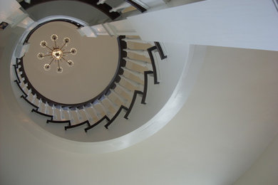 Large elegant wooden spiral staircase photo in New York with painted risers