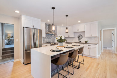 Inspiration for a large modern l-shaped light wood floor and brown floor eat-in kitchen remodel in Denver with a single-bowl sink, shaker cabinets, white cabinets, multicolored backsplash, ceramic backsplash, stainless steel appliances, an island and multicolored countertops