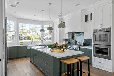 Kitchen - large transitional u-shaped medium tone wood floor and brown floor kitchen idea in Los Angeles with a farmhouse sink, shaker cabinets, green cabinets, quartz countertops, green backsplash, ceramic backsplash, stainless steel appliances, an island and white countertops