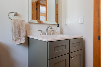 Powder room - small transitional light wood floor and brown floor powder room idea in Boston with shaker cabinets, green cabinets, a two-piece toilet, white walls, an integrated sink, quartz countertops, white countertops and a built-in vanity