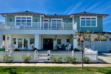 Mid-sized beach style green two-story concrete fiberboard and shingle house exterior photo in San Diego with a hip roof, a shingle roof and a black roof