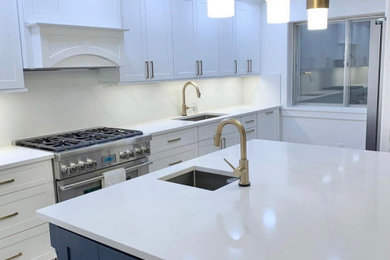 Example of a large minimalist u-shaped porcelain tile and beige floor eat-in kitchen design in New York with an undermount sink, shaker cabinets, white cabinets, quartz countertops, white backsplash, stone slab backsplash, stainless steel appliances, an island and white countertops