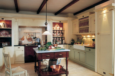 Mittelgroße Landhausstil Küche in L-Form mit Landhausspüle, Kassettenfronten, grünen Schränken, Arbeitsplatte aus Holz, Küchenrückwand in Grün, bunten Elektrogeräten, hellem Holzboden und Kücheninsel in Düsseldorf