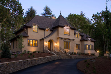 Design ideas for a mid-sized traditional two-storey stucco brown exterior in Other with a hip roof.