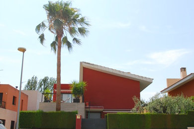 Foto de fachada de casa roja actual de tamaño medio de dos plantas con revestimiento de estuco, tejado de un solo tendido y tejado de varios materiales