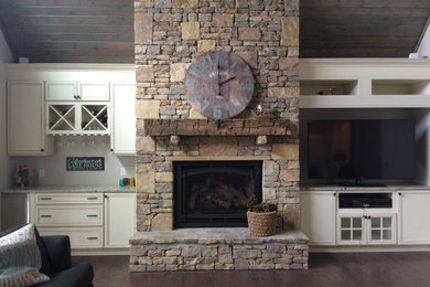 Large farmhouse open concept dark wood floor and brown floor living room photo in Other with a bar, a stone fireplace and a media wall
