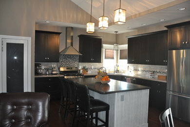 Mid-sized elegant l-shaped dark wood floor and brown floor open concept kitchen photo in Chicago with a double-bowl sink, shaker cabinets, dark wood cabinets, gray backsplash, stone tile backsplash, stainless steel appliances, an island and gray countertops
