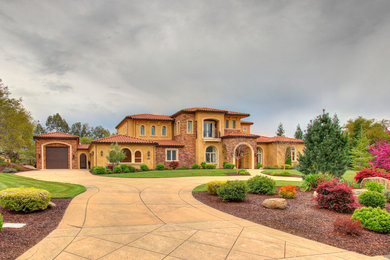 Photo of a large mediterranean two-storey stucco orange house exterior in Sacramento with a hip roof and a tile roof.