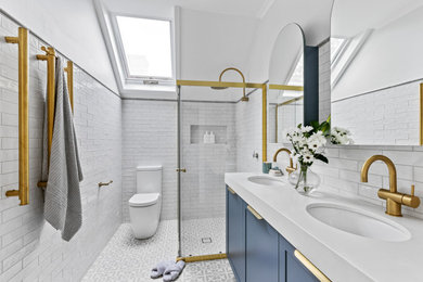 This is an example of a mid-sized 3/4 bathroom in Sydney with shaker cabinets, blue cabinets, a corner shower, a two-piece toilet, white tile, white walls, an undermount sink, grey floor, a sliding shower screen, white benchtops, a niche, a double vanity and a freestanding vanity.