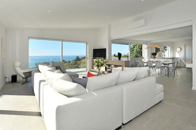 This is an example of a large beach style open concept living room in Other with white walls, a two-sided fireplace and grey floor.