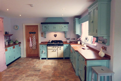 Foto de cocina romántica abierta sin isla con fregadero sobremueble, puertas de armario azules, encimera de madera y electrodomésticos con paneles