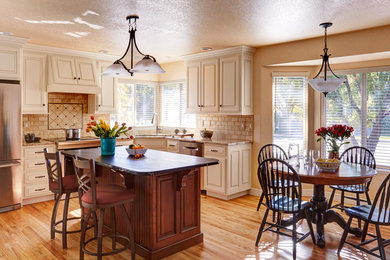 Mid-sized elegant l-shaped light wood floor eat-in kitchen photo in Denver with an undermount sink, raised-panel cabinets, beige cabinets, quartz countertops, beige backsplash, stone tile backsplash, stainless steel appliances and an island