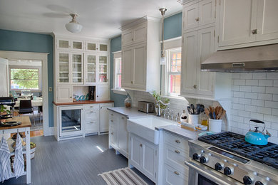 Mid-sized elegant galley linoleum floor kitchen pantry photo in Portland with a farmhouse sink, shaker cabinets, white cabinets, quartzite countertops, white backsplash, ceramic backsplash, stainless steel appliances and no island
