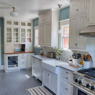 Photo of a mid-sized traditional galley kitchen pantry in Portland with a farmhouse sink, shaker cabinets, white cabinets, quartzite benchtops, white splashback, ceramic splashback, stainless steel appliances, linoleum floors and no island.