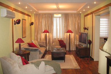 Imagen de salón abierto actual pequeño con paredes verdes, suelo de madera oscura y pared multimedia