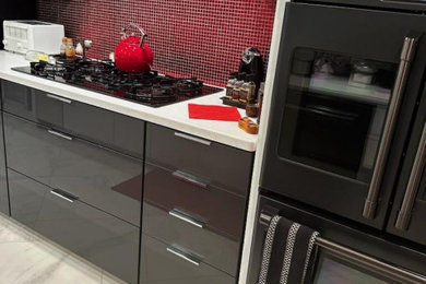 Large mid-century modern galley porcelain tile and white floor eat-in kitchen photo in Other with glass-front cabinets, gray cabinets, quartz countertops, red backsplash, glass tile backsplash, black appliances and white countertops