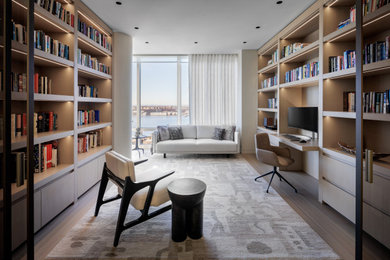 Mid-sized trendy built-in desk light wood floor and brown floor study room photo in New York with beige walls