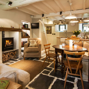 Kleines Country Esszimmer mit beiger Wandfarbe, Kaminofen, verputztem Kaminsims und schwarzem Boden in Cornwall