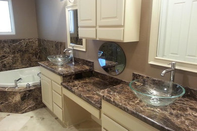 Mid-sized elegant master brown tile ceramic tile bathroom photo in Las Vegas with raised-panel cabinets, white cabinets, a hot tub, a one-piece toilet, beige walls and granite countertops