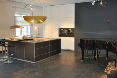 Modelo de cocina contemporánea de tamaño medio con fregadero bajoencimera, armarios con paneles lisos, electrodomésticos negros, suelo de pizarra, una isla y suelo negro