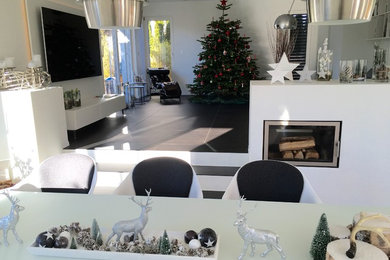 Geräumiges, Offenes Modernes Wohnzimmer mit weißer Wandfarbe, Schieferboden, Kaminofen, verputzter Kaminumrandung und TV-Wand in München