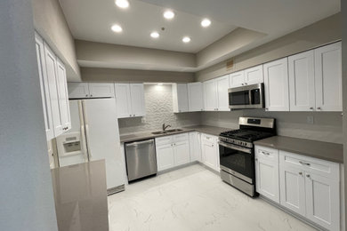 Example of a small trendy coffered ceiling kitchen design in Houston with shaker cabinets, white cabinets, quartz countertops, white backsplash, porcelain backsplash and gray countertops
