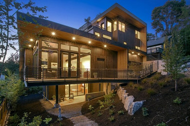 Inspiration for a large modern three-storey brown exterior in Seattle with a flat roof and wood siding.