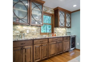 Eat-in kitchen - huge transitional medium tone wood floor eat-in kitchen idea in Minneapolis with an undermount sink, glass-front cabinets, dark wood cabinets, granite countertops, multicolored backsplash, stone tile backsplash, stainless steel appliances and a peninsula