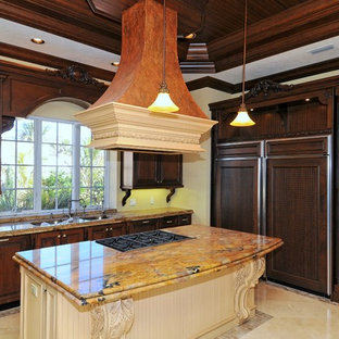 Неиссякаемый источник вдохновения для домашнего уюта: угловая кухня среднего размера в средиземноморском стиле с кладовкой, тройной раковиной, фасадами с выступающей филенкой, темными деревянными фасадами, столешницей из гранита, желтым фартуком, техникой под мебельный фасад, полом из травертина и островом