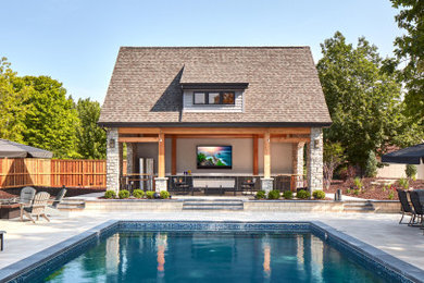 Photo of an expansive arts and crafts backyard rectangular lap pool in Other with a pool house and concrete pavers.