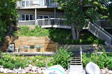 This is an example of a mid-sized rustic backyard stone retaining wall landscape in Milwaukee.