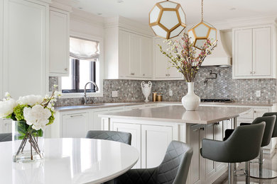Photo of a transitional l-shaped eat-in kitchen in Montreal with an undermount sink, shaker cabinets, white cabinets, quartzite benchtops, multi-coloured splashback, mosaic tile splashback and with island.