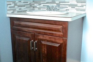 Bathroom - small craftsman 3/4 gray tile and glass tile ceramic tile bathroom idea in Vancouver with raised-panel cabinets, dark wood cabinets, a two-piece toilet, blue walls, a drop-in sink and laminate countertops
