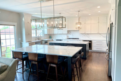 Eat-in kitchen - large transitional u-shaped medium tone wood floor and brown floor eat-in kitchen idea in Chicago with a farmhouse sink, shaker cabinets, white cabinets, quartz countertops, white backsplash, quartz backsplash, stainless steel appliances, two islands and white countertops