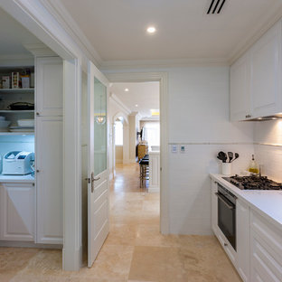 Large traditional kitchen pantry pictures - Inspiration for a large timeless galley travertine floor kitchen pantry remodel in Perth with shaker cabinets, white cabinets, solid surface countertops, white backsplash, subway tile backsplash, stainless steel appliances and an island