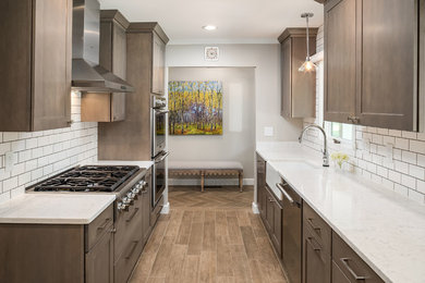 Photo of a mid-sized contemporary galley eat-in kitchen in Columbus with a farmhouse sink, shaker cabinets, grey cabinets, quartz benchtops, white splashback, subway tile splashback, stainless steel appliances, porcelain floors, no island, grey floor and grey benchtop.