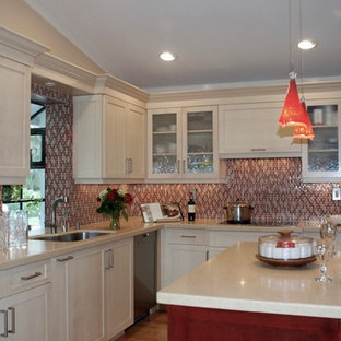 Inredning av ett klassiskt mellanstort kök, med en undermonterad diskho, skåp i shakerstil, röda skåp, bänkskiva i kvarts, rött stänkskydd, glaspanel som stänkskydd, rostfria vitvaror, mellanmörkt trägolv, en köksö och beiget golv