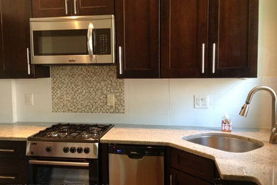 Small trendy l-shaped medium tone wood floor enclosed kitchen photo in Philadelphia with no island, an undermount sink, shaker cabinets, medium tone wood cabinets, granite countertops, white backsplash, ceramic backsplash and stainless steel appliances